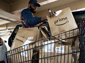 An independent contractor picks up an Amazon.com Inc. Prime grocery bag outside a Whole Foods Market Inc. store in Washington, D.C.