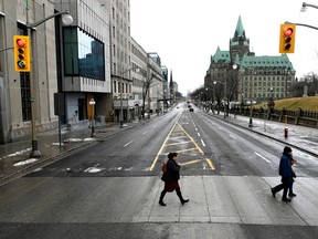 People cross the road on Wellington Street in Ottawa, the major street in front of Parliament Hill.