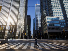 A woman crosses the street during morning commuting hours in the Financial District as Toronto copes with a shutdown due to the coronavirus, on April 1, 2020.