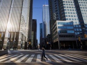 A woman crosses the street during morning commuting hours in the Financial District as Toronto copes with a shutdown on April 1, 2020.