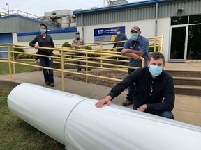 Johns Manville employees in Spartanburg, South Carolina, pose beside the nonwoven fabric that will be used for manufacturing of urgently needed disposable medical gowns used in the fight against the spread of COVID-19.