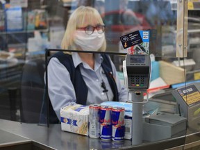 An cashier serves a customer behind a plastic shield to prevent the spread of coronavirus disease.