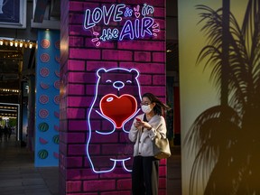 A woman wears a protective mask as she looks at her mobile phone in a shopping area on April 22, 2020 in Beijing, China.