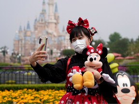 A visitor dressed as a Disney character takes a selfie while wearing a protective face mask at Shanghai Disney Resort as the Shanghai Disneyland theme park reopens.