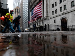 Two men wearing masks walks pass the New York Stock Exchange (NYSE) on April 30, 2020 in New York City.