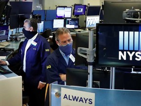 Traders wearing masks work, on the first day of in-person trading since the closure during the outbreak of the coronavirus disease on the floor at the New York Stock Exchange Tuesday.