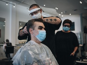 A stylist wearing a protective mask and face shield cuts a customer's hair at a salon in Coral Gables, Florida, U.S., on Monday, May 18, 2020.