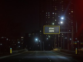 "Stay Home" is displayed on a sign over an empty road in Toronto, Ontario, Canada, on Wednesday, March 25, 2020.