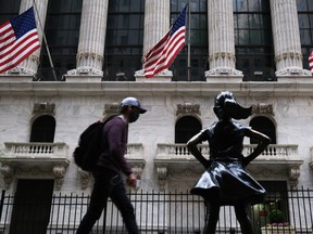 People walk by the New York Stock Exchange (NYSE) on May 18, 2020 in New York City.