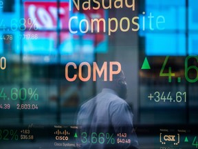 Monitors displaying stock market information are seen through the window of the Nasdaq MarketSite on April 6, 2020.