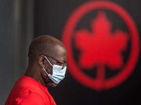 A person wearing a mask stands in front of the Air Canada moniker at Toronto Pearson Airport's Terminal 1.