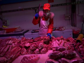 An employee chops pork meat at a market in Beijing, China.