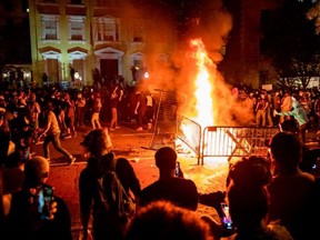 Protesters gather around a fire during a demonstration outside the White House over the death of George Floyd at the hands of Minneapolis Police in Washington, DC, on May 31, 2020.