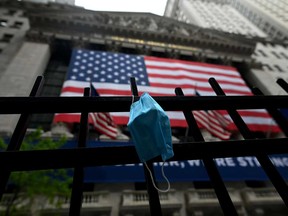 A face mask hangs on the fence in front of the New York Stock Exchange. Market sentiment is turning more negative on concern that the spreading coronavirus could force policy makers to slow the pace or reverse business re-openings.