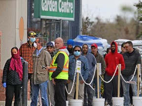 Shoppers wait in a physical distancing line-up to get into to the Rona store in Calgary.