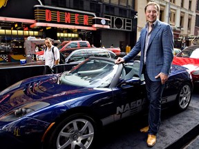 Elon Musk, chief executive officer of Tesla Motors, stands with the Tesla Roadster outside the Nasdaq in New York on the day his company went public on June 29, 2010.