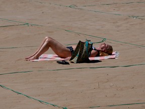 A woman sunbathes in a designated roped-off area on Poniente Beach in Benidorm on June 21, 2020, a day after the town's beaches were reopened after three months of closure due to a national lockdown to stop the spread of the novel coronavirus.
