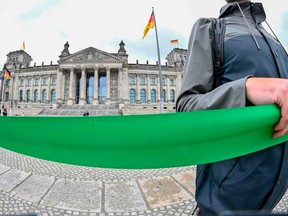 Demonstrators hold a green ribbon as they take part in a protest calling for a "Green Europe" on July 1, 2020 in front of the Reichstag building in Berlin.