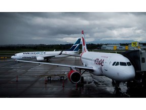 A Westjet Boeing 737-800, left, taxis past an Air Canada Rouge Airbus A319 at Vancouver International Airport in Richmond, B.C., on Monday, April 28, 2014. A new poll suggests turbulence ahead when it comes to the airlines winning public support for their current COVID-19 plans.