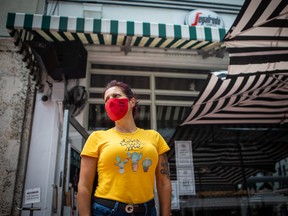 An employee wears a protective mask while waiting to seat customers outside a restaurant in Miami Beach, Florida.
