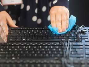 An employee cleans keyboards in preparation for returning workers at an office.