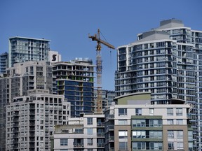A crane is seen between residential buildings in Vancouver, British Columbia, Canada, on Thursday, April 16, 2020.