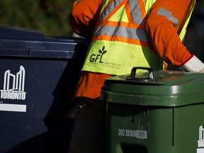 A GFL Environmental Inc. worker picks up household waste containers at a residential neighbourhood in Toronto.