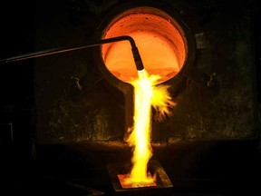 A worker pours melted gold into casts from a furnace at the ABC Refinery in Sydney, Australia.