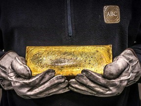 A worker hold a 20 kilogram gold brick at the ABC Refinery in Sydney.