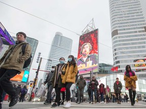 Pedestrians walk across Yonge Street in Toronto. For the first time Statistics Canada has tracked race-based data on job losses.