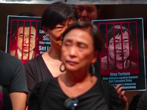 Portraits of detained Chinese human rights lawyers Jian Tianyong (L) and Wang Quanzhang are seen as Hong Kong pro-democracy activists observe a silent protest in support of human rights lawyers in China, outside the Court of Final Appeal in Hong Kong's Central district on July 9, 2017.