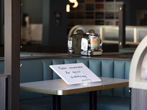 A social distancing sign is displayed at booth in a restaurant on the first day of indoor dining in Ottawa, in July.