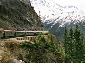 A White Pass and Yukon passenger train rounds a curve on the narrow-gauge track as it descends through the mountains to Skagway, Alaska.