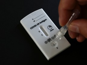 A health worker puts a sample into a COVID-19 antigen rapid test device at a testing station, in Vienna, Austria.