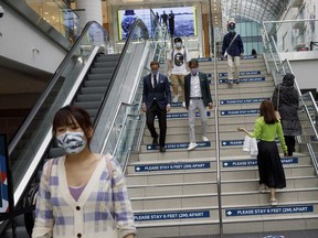 Shoppers wearing protective masks walk past right of way arrows inside the Eaton Centre in Toronto.