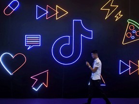 A man holding a phone walks past a sign of Chinese company ByteDance's app TikTok, known locally as Douyin, at the International Artificial Products Expo in Hangzhou, Zhejiang province, China October 18, 2019.