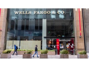 External view of Wells Fargo building with a glass front and individuals walking by on sidewalk.