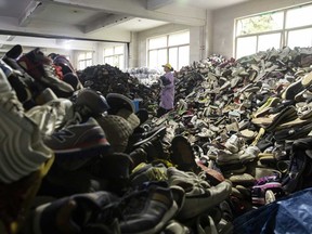 An employee walks past piles of used footwear at a sorting facility operated by second-hand clothing trading firm Baijingyu in Hangzhou, China.