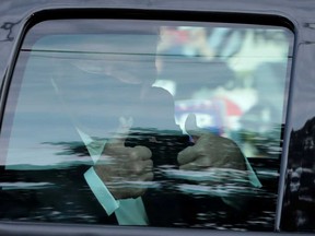 U.S. President Donald Trump gestures from a car Sunday as he rides in front of the Walter Reed National Military Medical Center, where he is being treated for the coronavirus disease in Bethesda, Maryland.