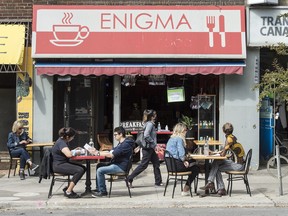Patrons sit outside of Toronto's Enigma restaurant on Bloor Street West as a pedestrian wearing a mask walks by, Monday September 21, 2020.