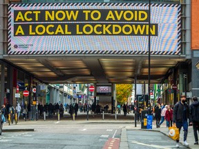 Pedestrians pass a large advertisement on the Arndale Centre shopping mall reading "Act now to avoid a local lockdown" in Manchester, U.K., on Friday, Oct. 16, 2020.