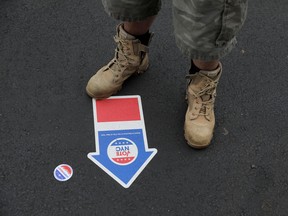 A person stands on a marker while waiting to enter a polling station to vote early at Our Lady Help of Christians in Staten Island, New York City, Oct. 25, 2020.