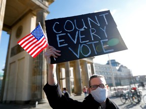 A demonstrator holds a placard and a U.S. flag during the "Count the Votes! Rally for Fair Elections in the USA" organized by Young Democrats Abroad following the 2020 U.S. presidential election, next to the Brandenburg Gate, in Berlin, Germany November 4, 2020.