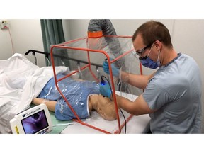 Dr. Marc Curial demonstrates use of the portable Aerosol Containment Tent (ACT) on a mannequin.