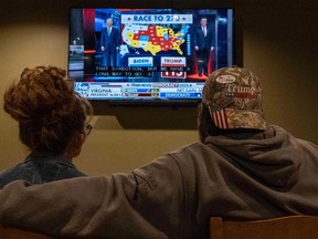 A couple watches the election results at a Republican watch party at Huron Vally Guns in New Hudson, Michigan on election night.