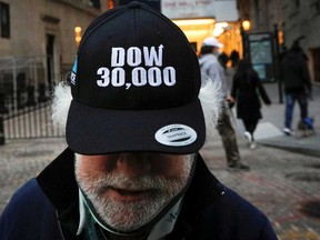 A trader wears a DOW 30,000 hat outside the New York Stock Exchange on Tuesday. The Dow slipped from this record high Wednesday in morning trading.