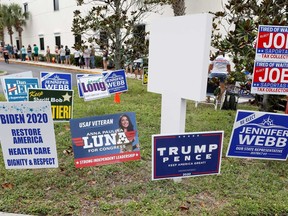 Campaign signs are posted near the Supervisor of Elections Office polling station while people line up for early voting in Pinellas County ahead of the election in Largo, Florida.