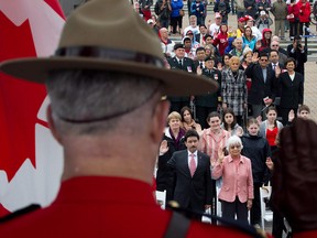 A Royal Canadian Mounted Police officer raises his hand as a group  takes the oath of citizenship  in Vancouver, B.C.