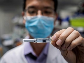This file photo taken on April 29, 2020 shows an engineer showing an experimental vaccine for the COVID-19 coronavirus that was tested at the Quality Control Laboratory at the Sinovac Biotech facilities in Beijing. (