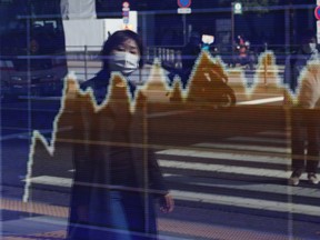 A woman is reflected in an electronic screen showing global stock market information on the street on Nov. 5, 2020 in Tokyo, Japan.